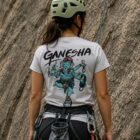 Escaladora de espaldas usando playera Ganesha gris de Belay Partners frente a pared de roca natural